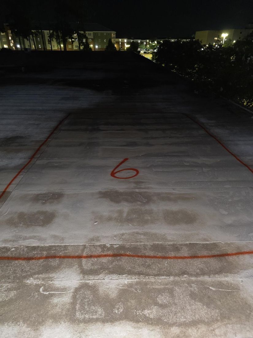A wet area outlined and numbered in orange paint on a white roof membrane